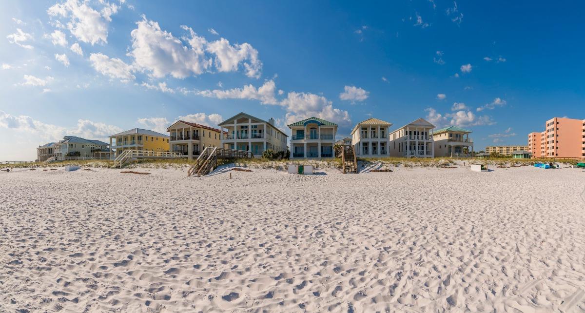 Destin Florida beach house rentals lined along white sand beach under a bright blue sky