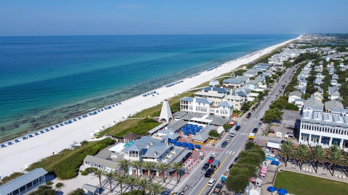 Aerial view of Destin’s coastline at sunset, showcasing white-sand beaches, crystal-blue water, and beachfront properties including Destin vacation rentals and Destin condos.